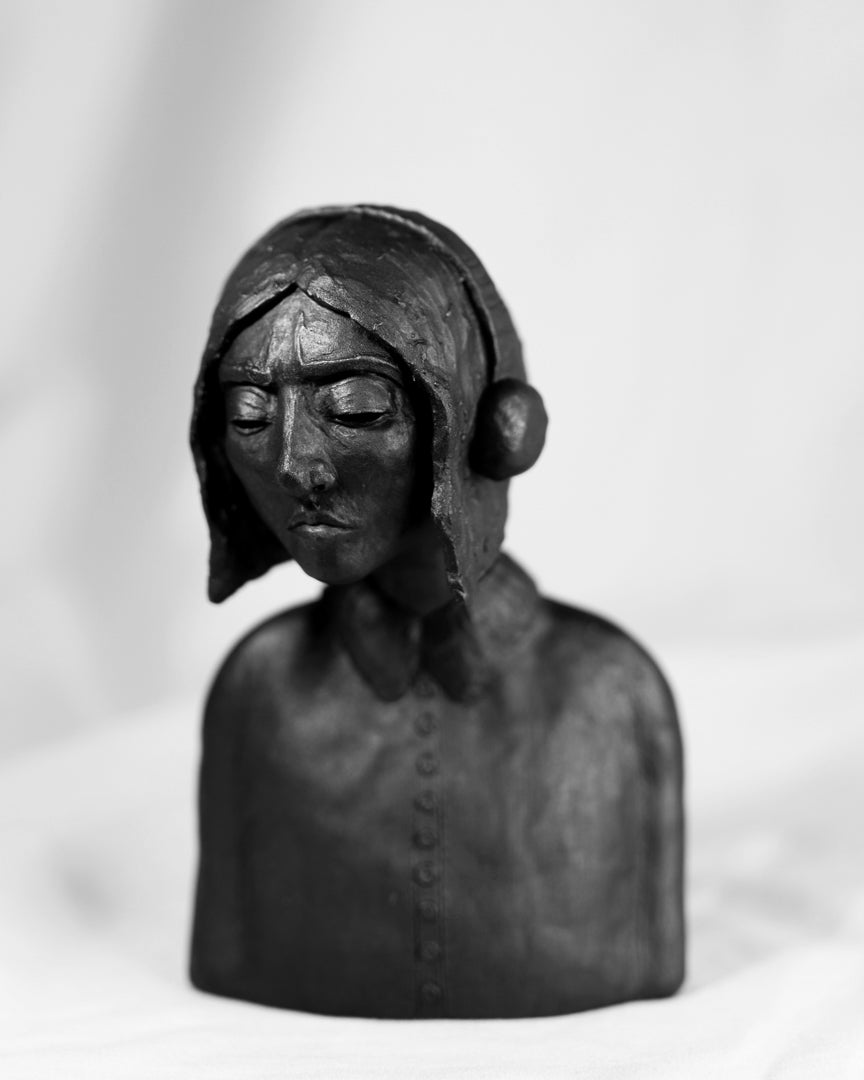 Ceramic sculpture of a forlorn woman looking down with headphones on.